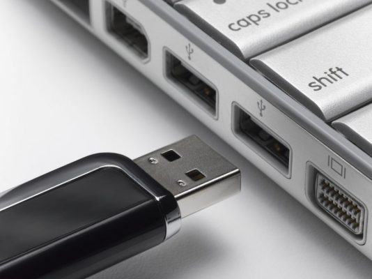 USB flash drive about to connect to laptop, close-up